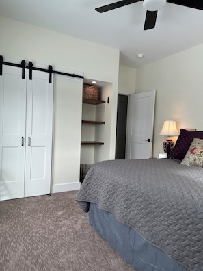 A bedroom with a bed, a wardrobe, a ceiling fan, and a lamp.