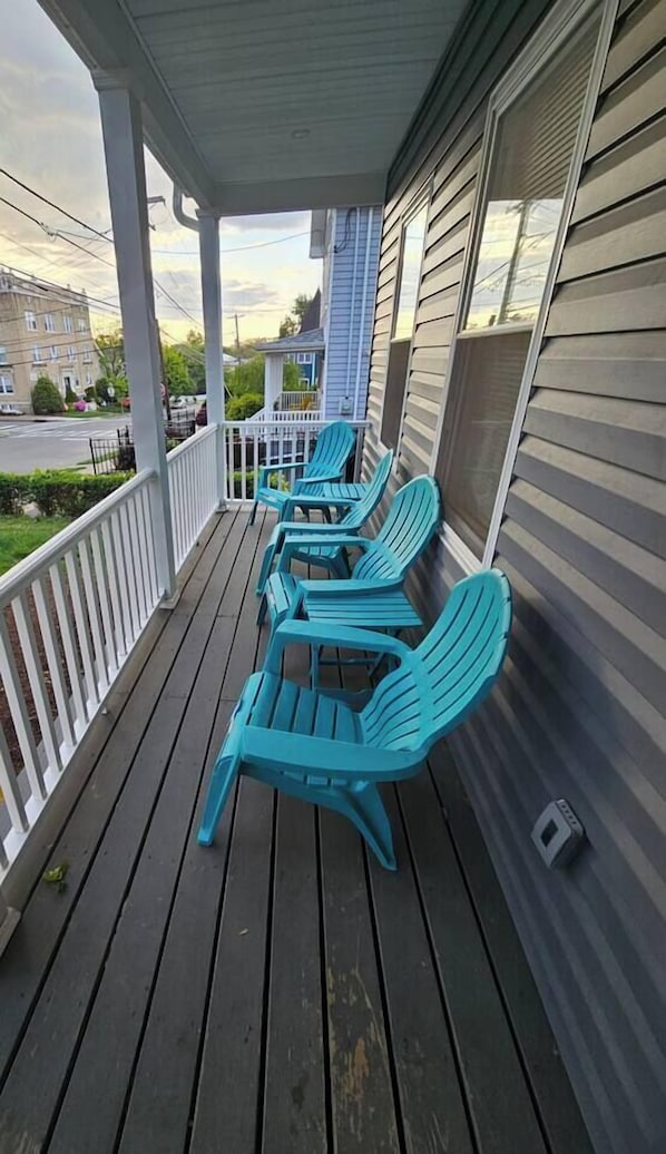 A covered porch with four turquoise Adirondack chairs.