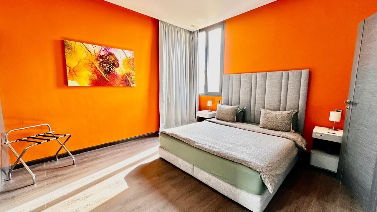 Ett modernt hotellrum med en stor säng, ett sidobord, en stol och en tavla på väggen.