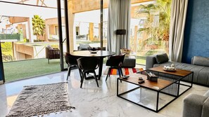 Ein modernes Wohnzimmer mit großem Fenster, einem runden Tisch und einer Couch.