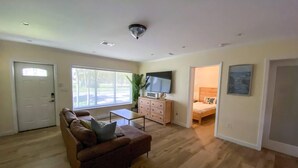 Ein Wohnzimmer mit Sofa, Fernseher und einer Tür zu einem Schlafzimmer.