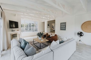 A modern living room with a sofa, coffee table, and a TV. - Stunningly decorated home with breathtaking views! (Helensvale)