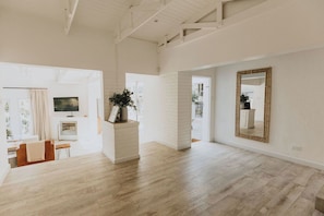 A spacious room with a wooden floor, a large mirror, and a fireplace. - Stunningly decorated home with breathtaking views! (Helensvale)