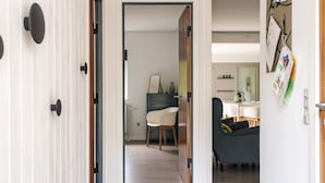 Ein Flur mit einer Holztür, einer weißen Wand mit einem Schwarmsbrett und einem Essbereich mit Tisch und Stühlen.