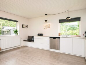 Une cuisine moderne avec des meubles blancs, un lave-vaisselle intégré et une fenêtre donnant sur un espace verdoyant.