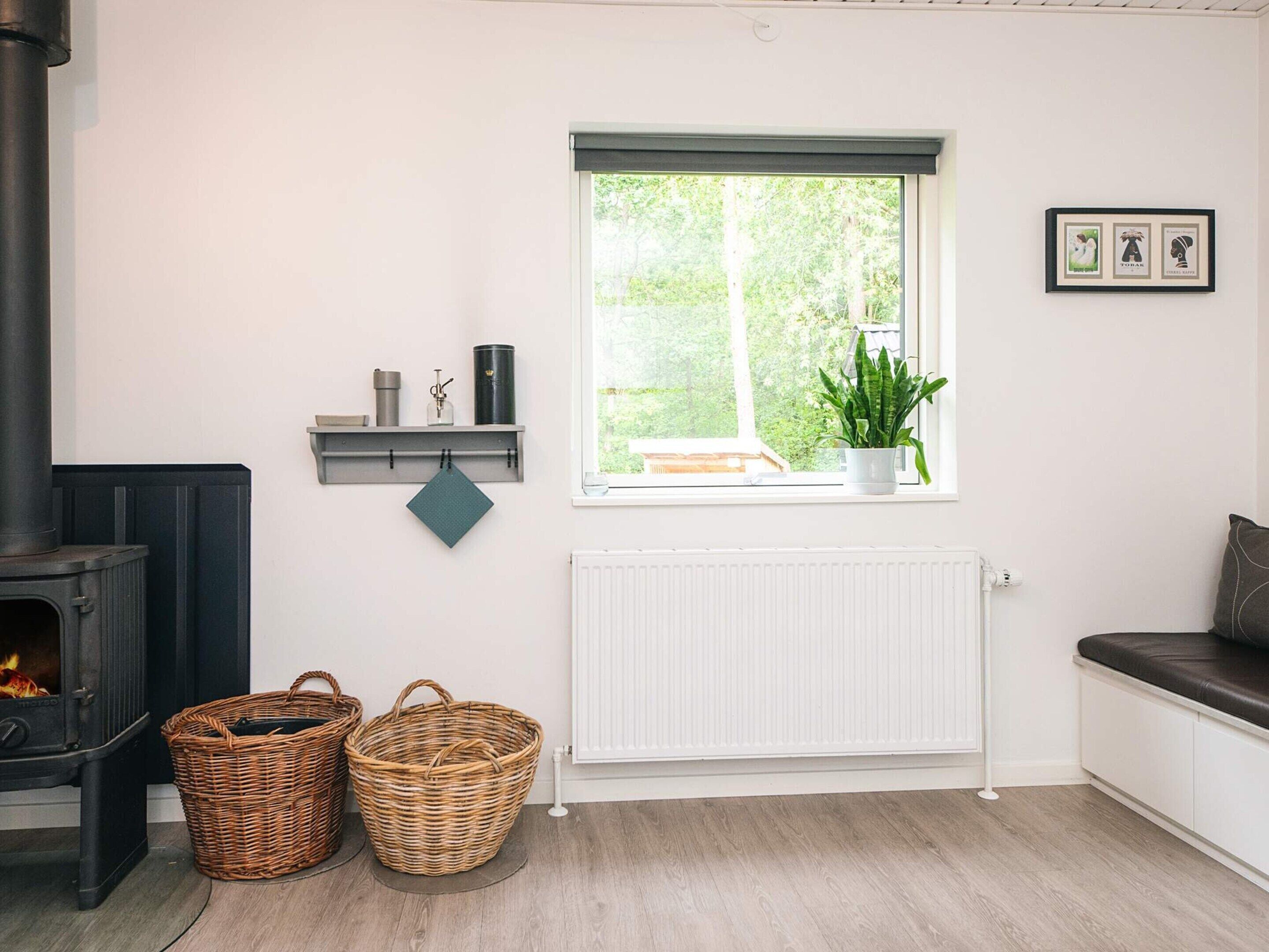 A cozy room with a fireplace, wicker baskets, a window with a view, and a radiator.