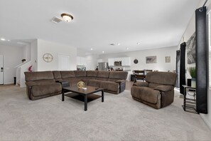 Ein modernes Wohnzimmer mit einer Eckcouch, einem Couchtisch und einem Essbereich mit einem Stuhl.