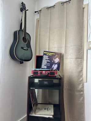 A guitar, a record player, and a poster on a shelf. - Stadium Stay! Cozy 2BR Steps from SoFi & Kia Forum (Inglewood)