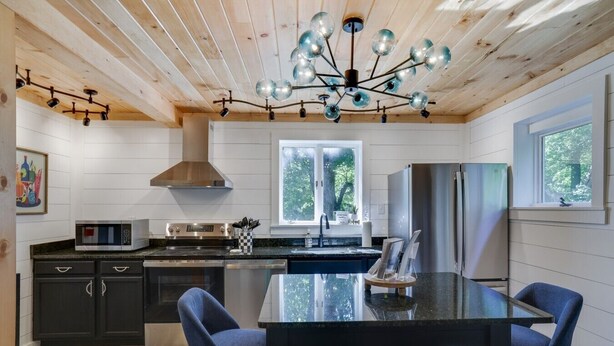 Una cocina moderna con una isla central, electrodomésticos de acero inoxidable y una lámpara de techo original.