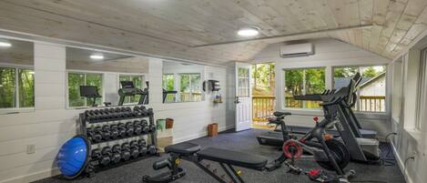 Een sportschool met loopbanden, een bankje, gewichten en een blauwe fitnessbal.