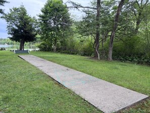 Ein Betonweg in einem Park mit einer Bank und Bäumen.