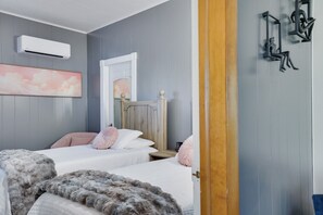 Ein Schlafzimmer mit zwei Betten, einem Spiegel, einer Klimaanlage und einem Bild an der Wand.