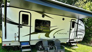 A camper with a covered living area, a small window, and a door.