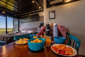 Un desayuno con una mesa de madera, cuencos azules y una cama con vistas.