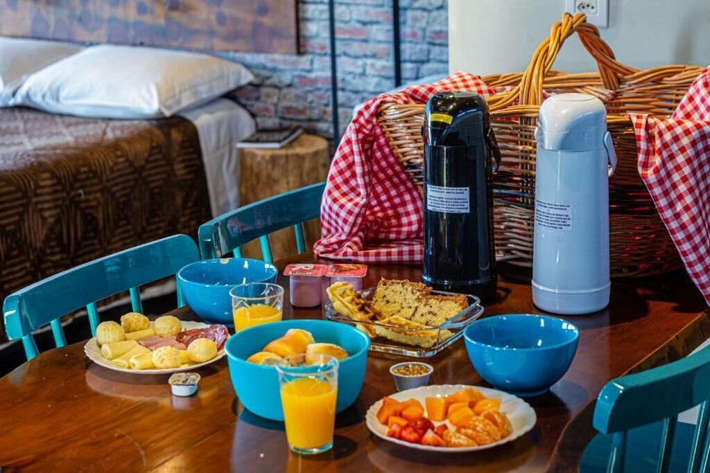Una mesa de desayuno con diversos alimentos, una cesta y una botella de agua.