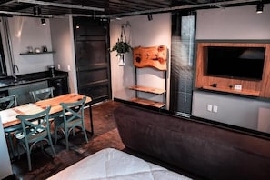 Eine moderne Küche mit Holztisch und -stühlen, einem integrierten Fernseher und einer Sitzecke mit Sofa und Kissen.