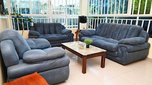 Uma sala de estar com dois sofás cinzentos, uma mesa de centro e um vaso de planta.