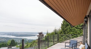 Un balcon offrant une vue sur le paysage urbain et un pont, un plafond en bois et une rambarde en métal.