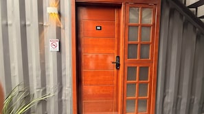 A wooden door with a number plate, a no-smoking sign, and a vertical striped wall. - LOFT127 - 04 (Itajaí)