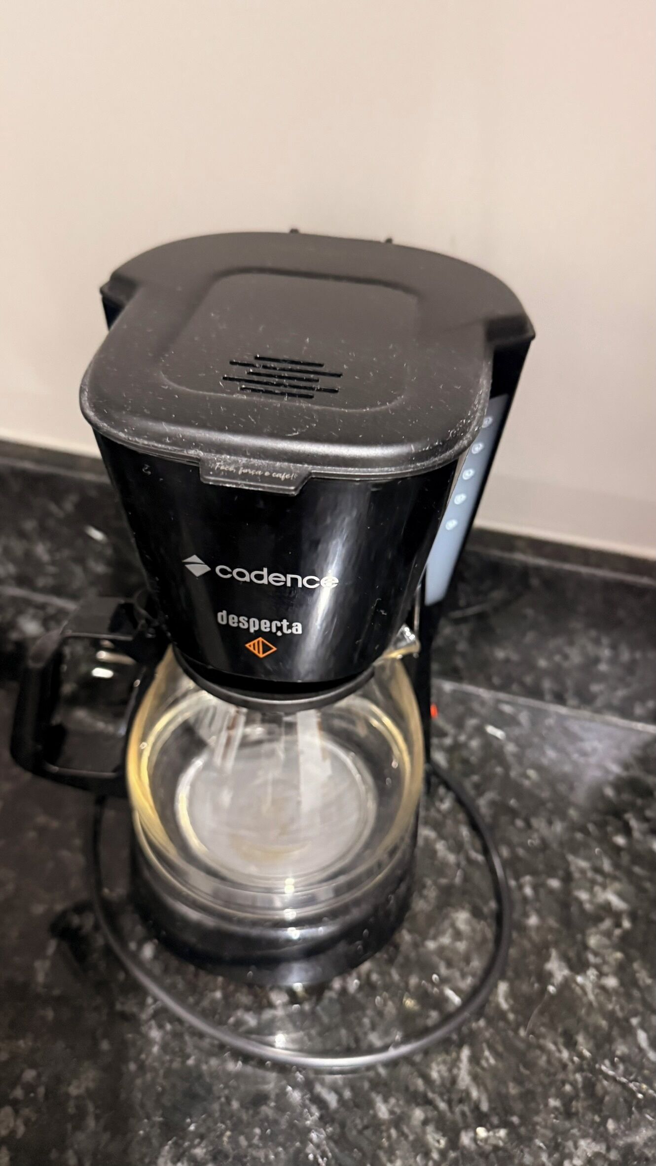Une machine à café dotée d’une verseuse en verre transparent, de la marque « Cadence », et sur laquelle on peut lire le mot « desperta ».