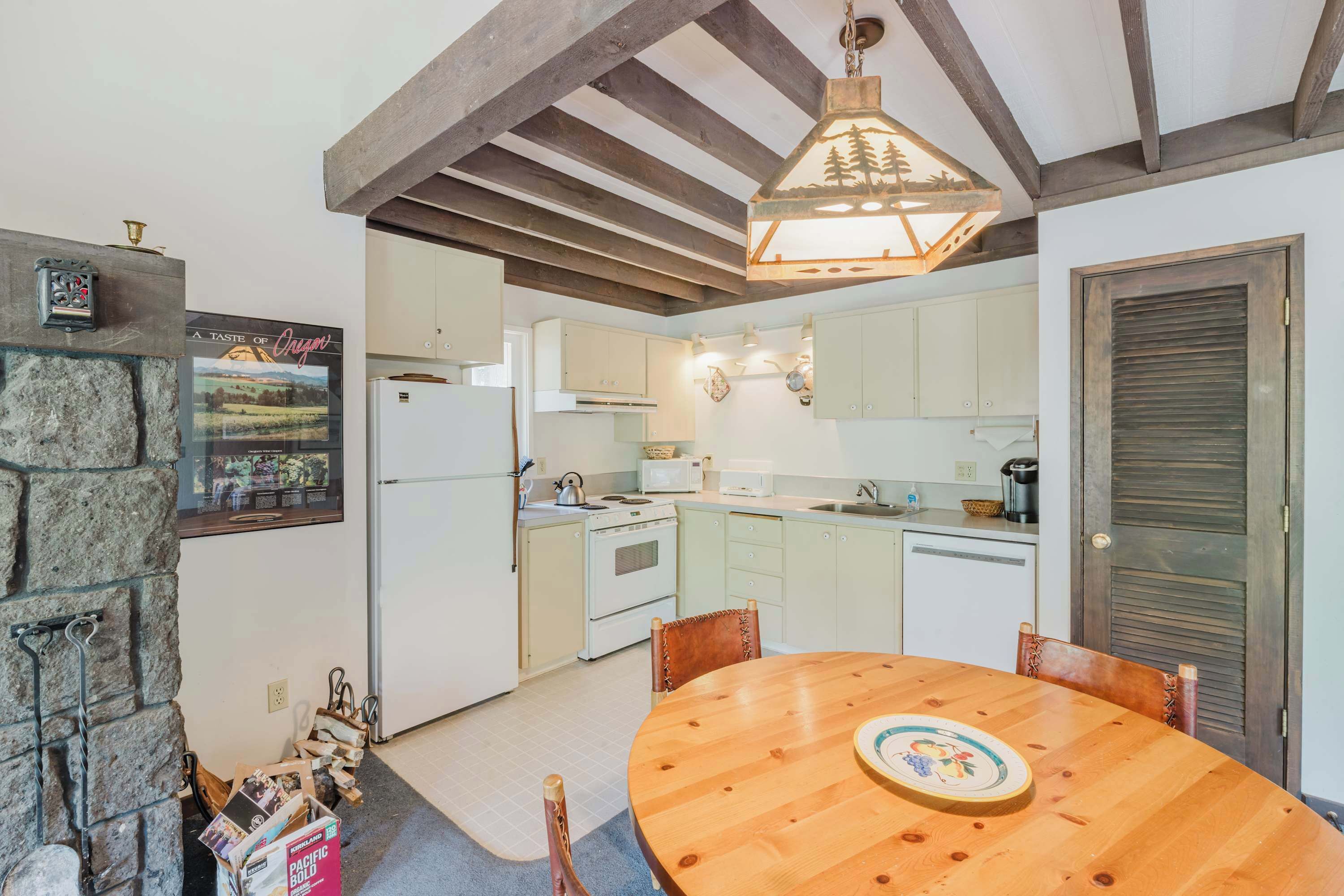 Een keuken met witte kastjes, een houten eettafel en een stenen muur.