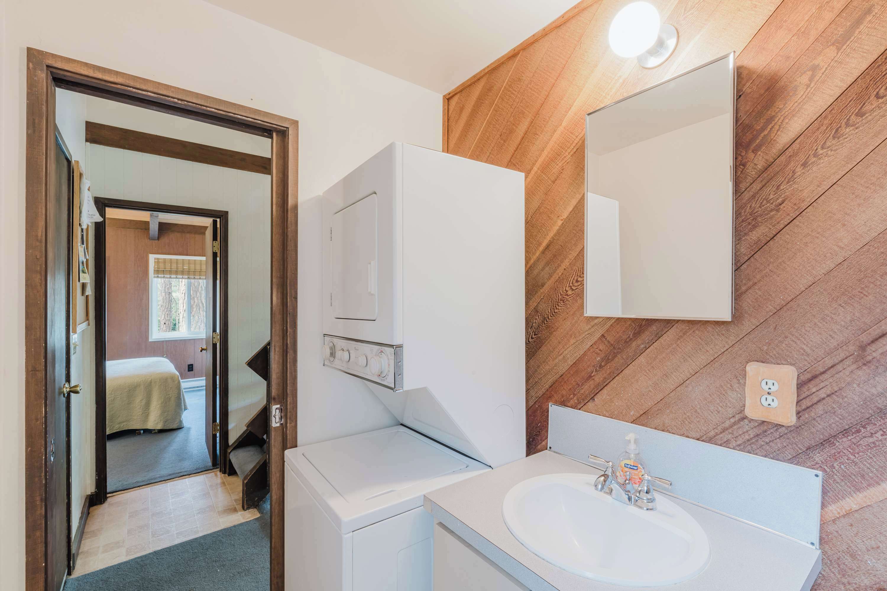Une salle de bain avec un mur en bois, un lavabo blanc et un miroir.