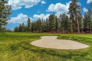 A golf course with a sand bunker, surrounded by tall pine trees and a clear blue sky. - Black Butte Retreat w Resort Amenities, Near Hiking and Bike Trails (Sisters)