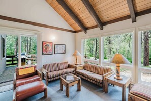 A cozy living room with a wooden ceiling, large windows, and a view of the forest. - Black Butte Retreat w Resort Amenities, Near Hiking and Bike Trails (Sisters)
