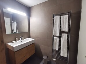 A modern bathroom with a white sink, wooden vanity, a mirror, and a towel rack. - The Marmot of Täsch (Täsch)