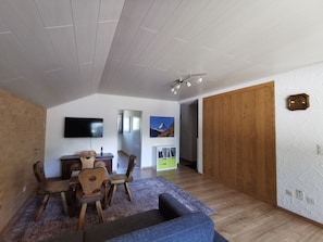 Un salon avec un téléviseur, des meubles en bois, un canapé et une porte en bois.