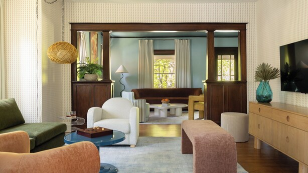 Un salon comprenant un canapé, des fauteuils, une table basse, un téléviseur et un meuble en bois.
