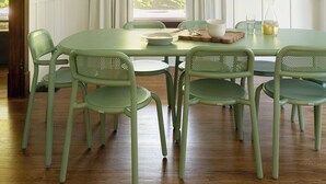 Un coin repas comprenant une table ronde, six chaises, un lustre et une fenêtre avec des rideaux.