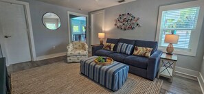 Un salon comprenant un canapé, un pouf, un fauteuil et des éléments de décoration murale.