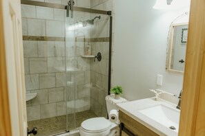 Ein Badezimmer mit Duschkabine, Toilette, Waschbecken und Spiegel.