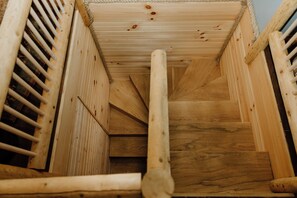 Eine Holztreppe führt nach unten, umgeben von vertikalen Hol zleisten, mit einem Seil an der Decke.