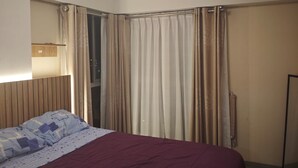 Ein Hotelzimmer mit Bett, Vorhängen, einem Spiegel und einer Deckenleuchte.