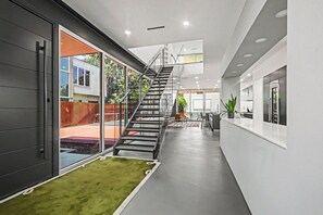 A modern interior with a staircase, a reception desk, and a view through glass doors. - Luxury Houston Home! (Houston)