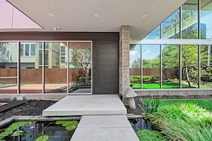 A modern building with large windows, a concrete pathway, and a small water feature with lily pads. - Luxury Houston Home! (Houston)