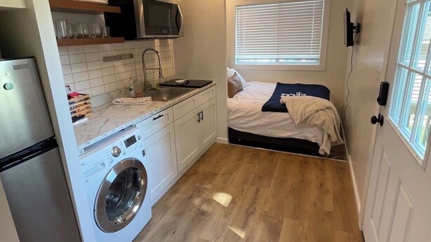A compact kitchen with a washing machine, microwave, and sink. - Tiny House near Hillsdale College (Hillsdale)
