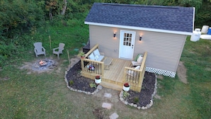 A small wooden cabin with a deck, outdoor seating, and a fire pit. - Tiny House near Hillsdale College (Hillsdale)