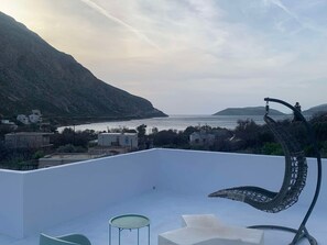 A rooftop terrace with a view of the sea and mountains, a metal sculpture, and a table. - Elena Arginonta Beach House Ground-Floor Apartment (Arginonta)