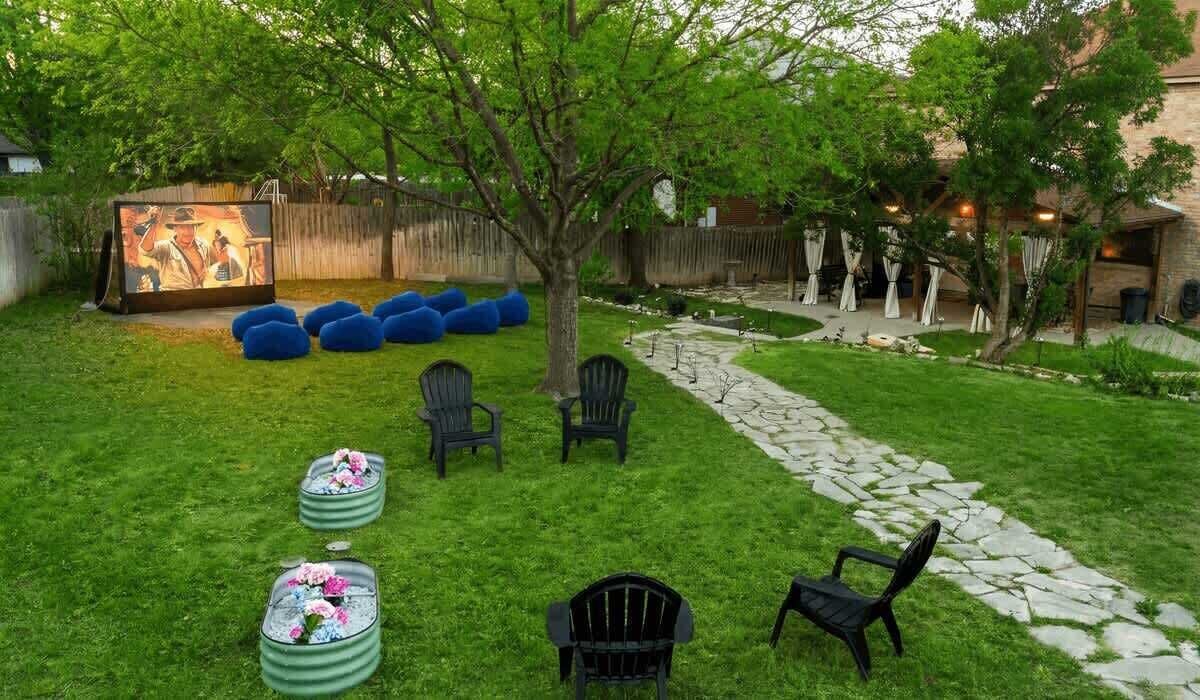 A backyard with a seating area, a tree, and a stone pathway.