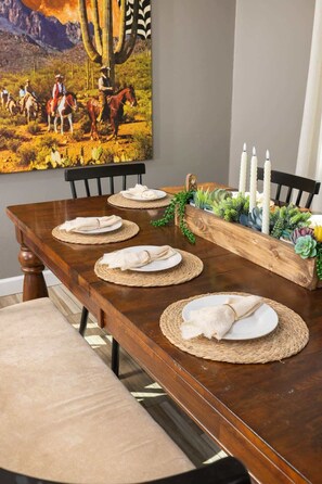 A dining table set with placemats, plates, and candles, with a painting and a wooden planter with succulents on the wall. - Heated Pool • Game Rm • Theater • Firepit • Pets (San Antonio)