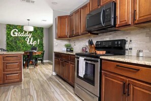 Une cuisine moderne avec des meubles en bois, une cuisinière en acier inoxydable et un four à micro-ondes.