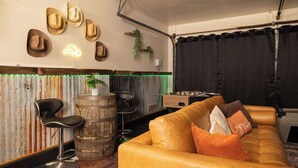 A cozy living area with a leather sofa, a bar stool, and a rustic barrel. - Heated Pool • Game Rm • Theater • Firepit • Pets (San Antonio)