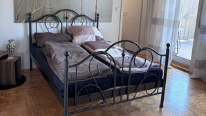 Een slaapkamer met een bed, houten plafond, een schilderij en uitzicht door een raam.