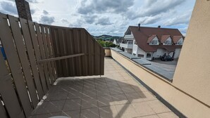 Een balkon met uitzicht op huizen en een bewolkte lucht.
