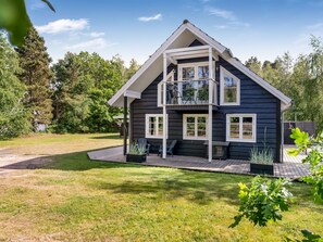 Een huis met twee verdiepingen, een balkon, een terras en een verzorgd gazon.