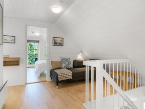 Ein geräumiges Schlafzimmer im Loft-Stil mit großem Fenster, einer gemütlichen Sitzecke und einer weißen Wendeltreppe.