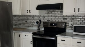 A kitchen with white cabinets, a stainless steel refrigerator, a black stove, and a microwave. - World Cup Gem 12 minutes from all attractions (Kansas City)